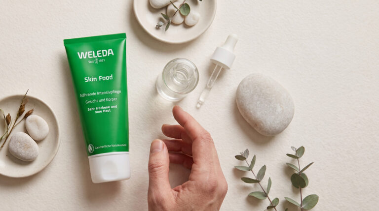 Weleda Skin Food Tube mit Pipette, Steinen und Eukalyptus auf hellem Hintergrund